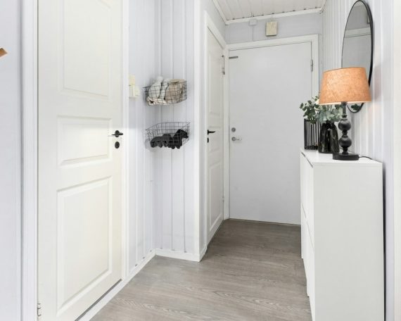 A white hallway with a mirror and coat rack
